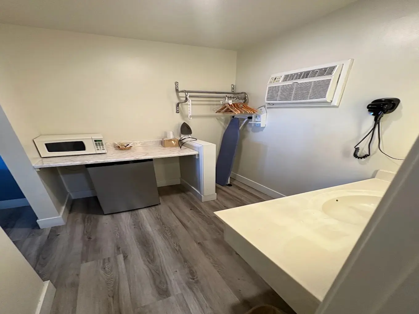 Guest room vanity with microwave, clothes rack, and wall-mounted hair dryer